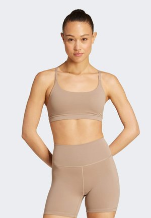 Light beige sports bra and high-waisted shorts made of smooth, stretchy fabric. Features thin straps and a fitted design, ideal for activewear.