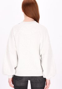 Maglione grigio chiaro con una finitura testurizzata, maniche ampie a palloncino e orlo a coste. Presenta un collo rotondo e dettagli di cucitura discreti.