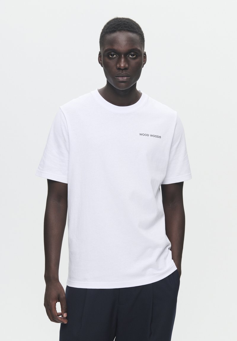 Vit bomull t-shirt med korta ärmar, med en liten "WOOD WOOD" logotyp i svart på vänster bröst. Enkel, avslappnad passform.