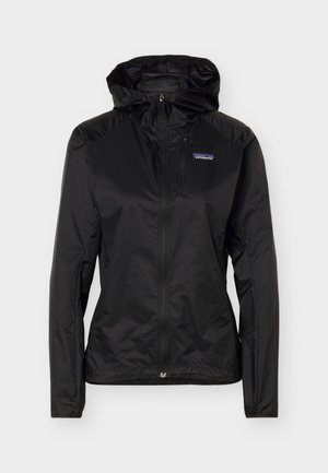 Μαύρο ελαφρύ μπουφάν με φερμουάρ πλήρους μήκους και κουκούλα, με τσέπη με φερμουάρ στο στήθος και λογότυπο της Patagonia στο αριστερό μέρος του στήθους, σχεδιασμένο για υπαίθρια χρήση.