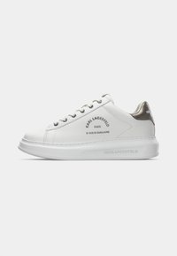 Hvit lav tennis med sølv hæltaffel, "Karl Lagerfeld Paris" tekst på siden, snøring foran og tykk hvit såle.