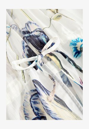 Doorzichtig stof met bloemenpatroon, met blauwe en paarse bloemen op een witte achtergrond, vastgemaakt met een zachte witte strik.