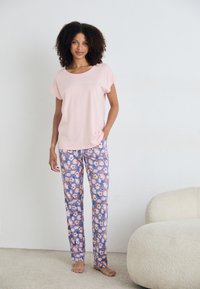 Šviesiai rožinė trumpomis rankovėmis palaidinė su tekstu, derinama su gėlių rašto pižamos kelnėmis mėlynos, oranžinės ir rožinės spalvų. Minkšta medžiaga.