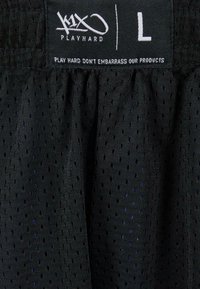 Svart idrettsshorts laget av teksturert mesh-stoff med små hull. Har et strikk med merkevarenavn og størrelse "L."