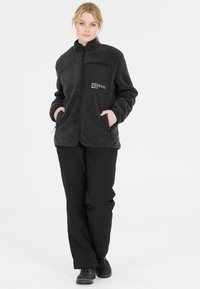 Svart fleecejacka med dragkedja fram, hög krage och sidfickor. Har en kontrasterande tygpanel med logodetalj. Slim-fit stil.