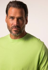 Světlý zelený bavlněný tričko s krátkým rukávem a kulatým výstřihem, s hladkou texturou a minimalistickým designem. Bez viditelných vzorů nebo akcentů.