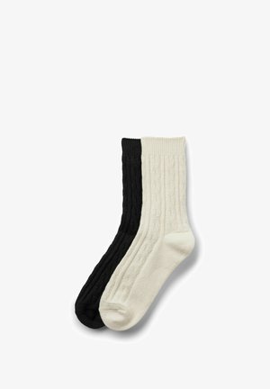 Due paia di calzini a coste in nero e crema. Il calzino nero presenta un design testurizzato; il calzino crema ha una finitura liscia.