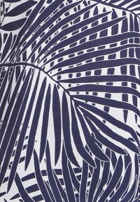 Tmavě modrá a bílá látka se vzory velkých, výrazných palmů, s tlustými a tenkými liniemi, vytvářejícími texturovaný vizuální kontrast.