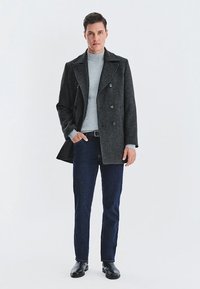 Ciemnoszara wełniana peacoat w podwójnie zapiętym stylu, noszony na jasnoszary golf. Ciemne dżinsy i czarne skórzane botki.