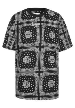 Camiseta oversized en blanco y negro con un patrón de paisley y diamante, cuello redondo y mangas cortas, con una textura suave de algodón.