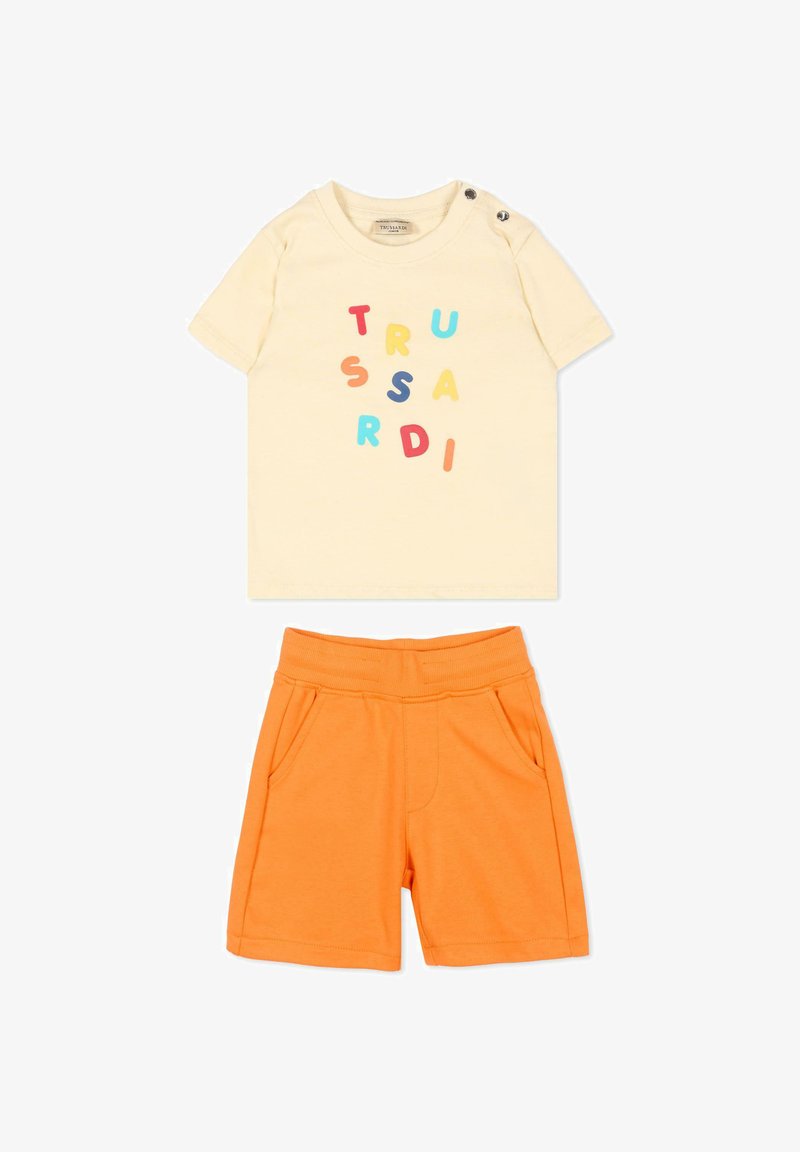 T-shirt crème manches courtes pour tout-petit avec des lettres colorées éparpillées et un short orange élastique à la taille avec poches.