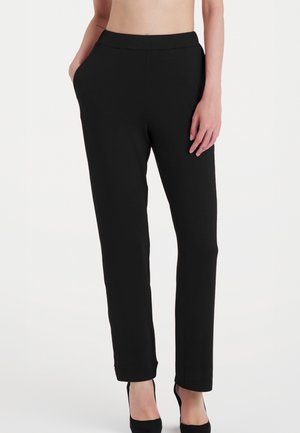 Pantaloni neri elasticizzati fatti di tessuto morbido, dotati di tasche laterali, una cintura liscia e gambe affusolate, adatti per uscite casual o semi-formali.