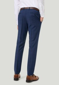 Marineblaue maßgeschneiderte Hose mit schmaler Passform, flachem Vorderteil und zwei Gesäßtaschen, kombiniert mit braunen Lederschuhen.