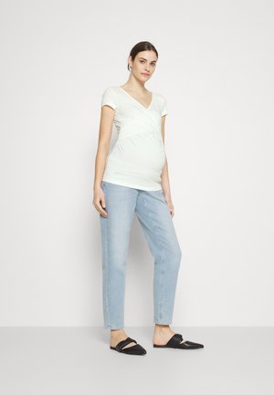 Light green wrap t-shirt with short sleeves, elastic stretch for belly support, paired with light blue straight-leg jeans and black slip-on shoes.