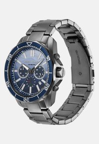 Zegarek ze stali nierdzewnej z niebieską tarczą, srebrnymi znacznikami godzinowymi, sub-tarczami chronografu oraz metalową bransoletą. Wodoodporny do 100 metrów.