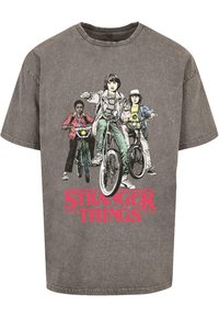 Grå grafisk t-skjorte med et vintage design av tre barn på sykler, med "STRANGER THINGS" i fet rød skrift nederst.