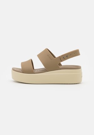 Beige platformsandal med to brede remme og en justerbar bagrem på en tyk cremefarvet sål.