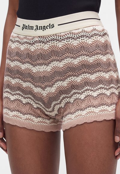 Shorts tricotés à bords festonnés avec motifs en zigzag rose et blanc, dotés d'une taille élastique blanche avec le texte "palm angels" en noir.