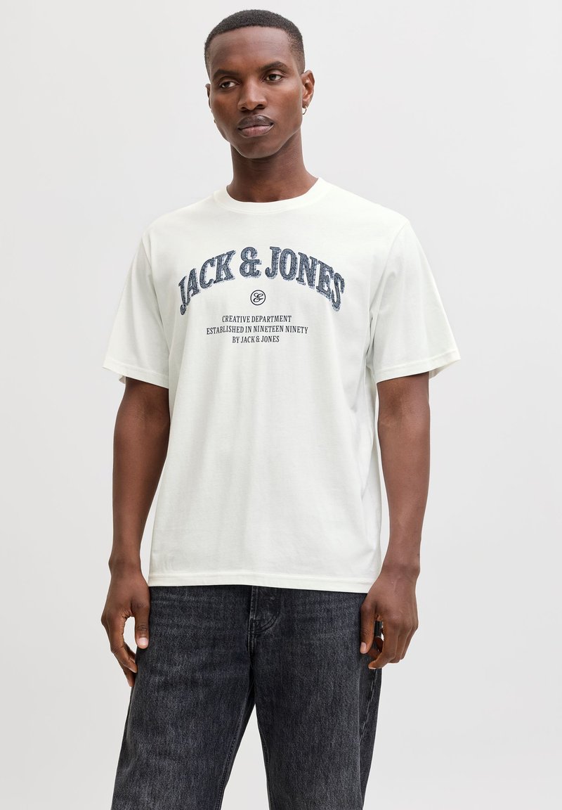 Hvid bomuld T-shirt med marineblåt grafisk tekst "JACK & JONES" og mindre tekst nedenunder, rund halsudskæring og korte ærmer.
