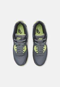 Nike Air sneakers featuring a gray mesh upper, neon green accents, gray laces, and textured soles for grip and support.