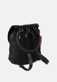 Mochila negra de nailon con un diseño acolchado, que cuenta con un asa trenzada en la parte superior, herrajes plateados y correas ajustables. Incluye un detalle de bolsillo lateral.