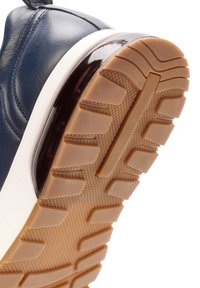 Marineblauwe leren sneaker met witte tussenzool en een bruine rubberen zool, voorzien van een diep loopprofiel voor grip.