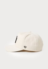 Casquette en coton beige avec un visière courbée, logo noir brodé sur le devant et petit détail '47' sur le côté. Texture lisse.