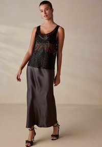 Must mustriga mustri üle siidise tumeda halli maksiseeliku, millel on sobiv siluett ja rihmikud, kaunistatud kontsad.