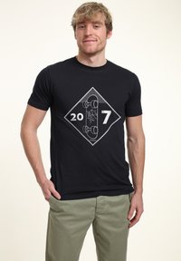 Černé bavlněné tričko s bílou diamond-shaped grafikou, která zobrazuje design skateboardu a čísla "20 7" na přední straně.