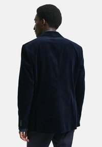 Navyblaues Corduroy-Sakko mit taillierter Passform, mit Schößchen und einem mittigen Schlitz. Verfügt über geknöpfte Manschetten und einen strukturierten Stoff.