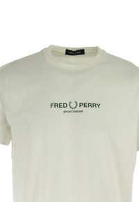 Cremefarvet bomulds T-shirt med teksten "FRED PERRY" i mørkegrøn, med et laurbærlogo ovenfor og "SPORTSWEAR" nedenfor. Klassisk rund hals.