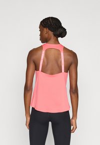 Ροζ αθλητικό τοπ με σχέδιο πίσω μέρος με άνοιγμα και λουριά με επωνυμία. Κατασκευασμένο από απαλό, ελαστικό υλικό, με άνετη εφαρμογή στο τελείωμα.