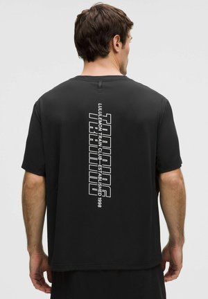 Svart träningsskjorta med korta ärmar i lätt tyg. Har vertikal vit text på baksidan, med rundad halsringning och avslappnad passform.