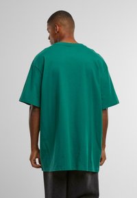 Oversized green t-shirt in cotton with short sleeves and a crew neck. Smooth texture, straight hem, and relaxed fit.