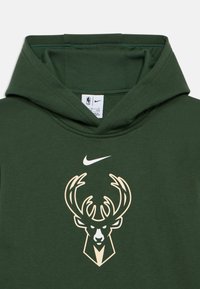 Zelená mikina s kapucí vyrobená z bavlny. Na hrudi se nachází béžové logo jelena s parohy a bílé logo Nike swoosh.