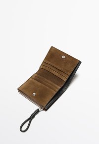 Portafoglio in suede marrone con esterno in pelle nera, dotato di varie fessure per carte, chiusura a scatto e zip con un tirante in pelle.