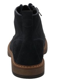 Botas de tobillo de ante azul marino con cremallera lateral y suela de goma marrón, que cuentan con un acento cosido a lo largo de la suela y un logo en el tacón.