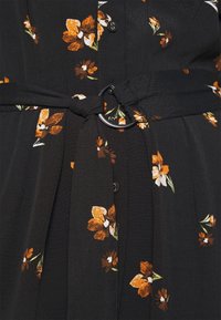 Svart klänning med orange och vita blommönster, med en knapplist framtill, ett tygbälte med en rund spänne och texturerat material.