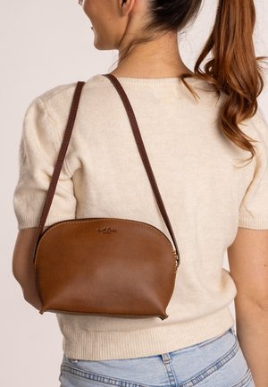 Braune Lederhandtasche mit runder Form, Reißverschluss und langem Trageriemen. Besitzt dezente Markenkennzeichnung auf der Vorderseite und eine glatte Textur.