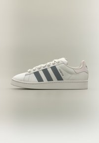 Pantof sport alb cu partea superioară din material texturat, trei dungi gri închis, design cu șireturi și o buclă la călcâi accentuată cu roz. Talpă plată din cauciuc.