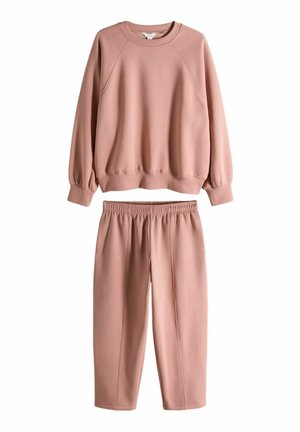 Ružová mikina a zodpovedajúce tepláky vyrobené z jemnej tkaniny. Mikina má okrúhly výstrih a raglánové rukávy; tepláky majú elastický pás.