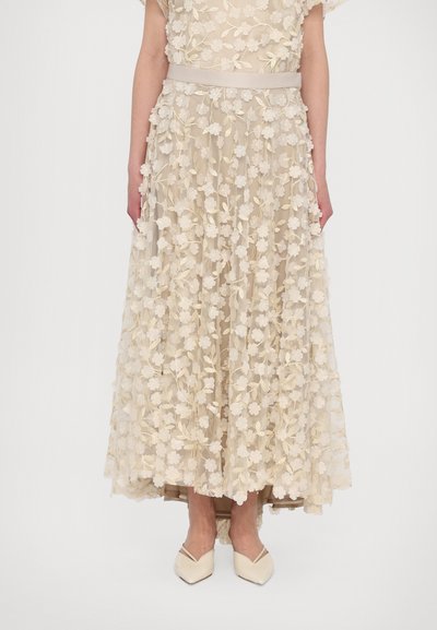 Lang, beige kjole med broderede blomsterdetaljer og bælte i taljen, med en gennemsigtig overdel og et lagdelt kantdesign.