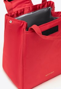 Červená izolační taška s texturovaným povrchem, vybavená pevnými uchy a černým suchým zipem. Interiér je podšitý šedou látkou.