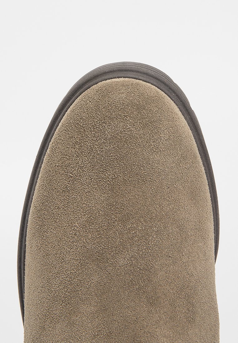 Bruine suède enkellaars met een ronde neus en een gladde rubberen zool. De gestructureerde afwerking verbetert grip en duurzaamheid.