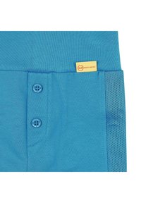 Top de algodón azul con dos botones decorativos, una etiqueta que dice "Steiff", y detalles de malla en un lado para mayor transpirabilidad.