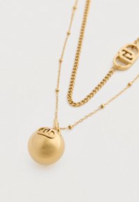 Gyldentoneet halskæde med en poleret sfærisk vedhæng og matchende kæde med et lille sammenkædet logo charme på en hvid baggrund.