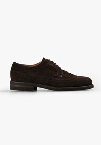 Zapato oxford de ante marrón con puntera de alas y tacón plano, que presenta perforaciones decorativas a lo largo de las costuras y un acabado superior suave.