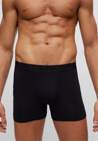 Schwarze Boxershorts aus glattem Stoff mit schlichtem Design. Mit einem Logo-Gummibund und einer taillierten Passform. Keine sichtbaren Muster oder Akzente.
