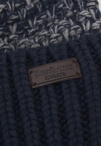 Knitted navy beanie featuring a textured pattern, with a brown leather label embossed with "Barbour" and "ENGLAND."