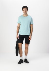 Világoskék rövid ujjú póló, fekete rövidnadrág, fekete sportcipő, fehér zokni és egy fekete tote táska. Minimalista design, látható minták nélkül.